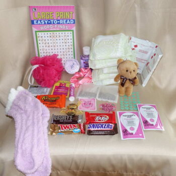 Deluxe monthly menstrual box products displayed with feminine hygiene pads and indulgent healthy snacks.