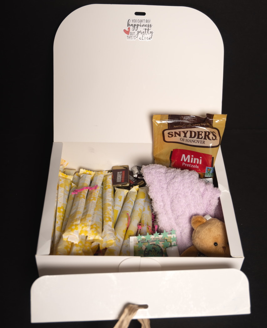 Period box care package with feminine essential pads/tampons, spa worthy products, and sweet and salty delectables.